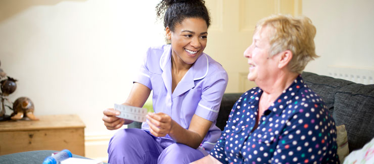 Female home care worker helps elderly woman with Alzheimer's take her medication.