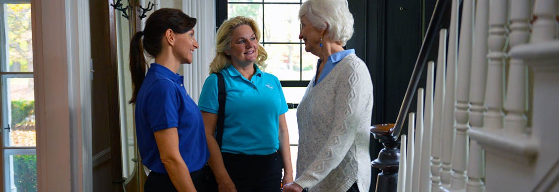 Two caregivers answer questions to an elderly woman looking for home care.