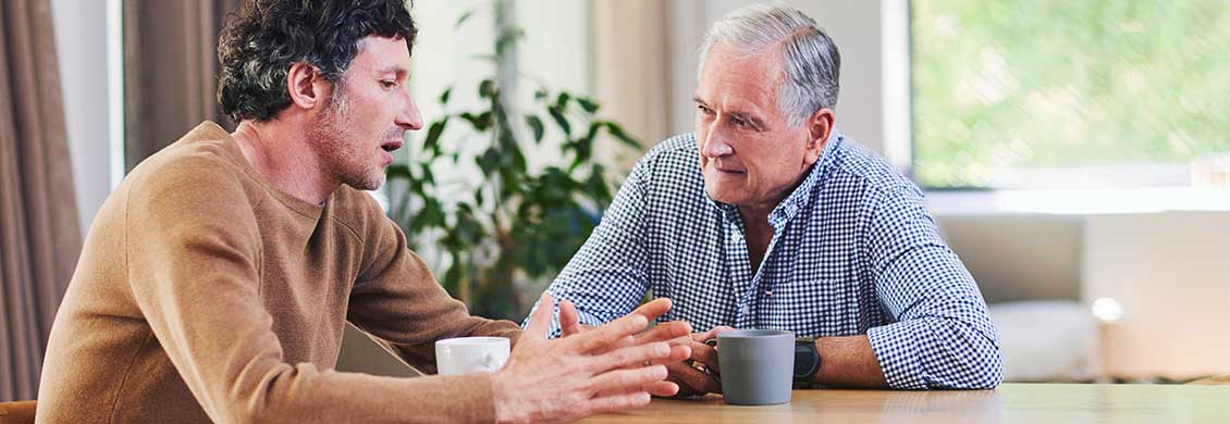 Mid-adult man discusses home care costs with father.