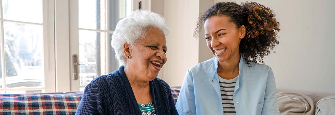 Home care provider laughing with an elderly woman who is receiving compassionate palliative care.