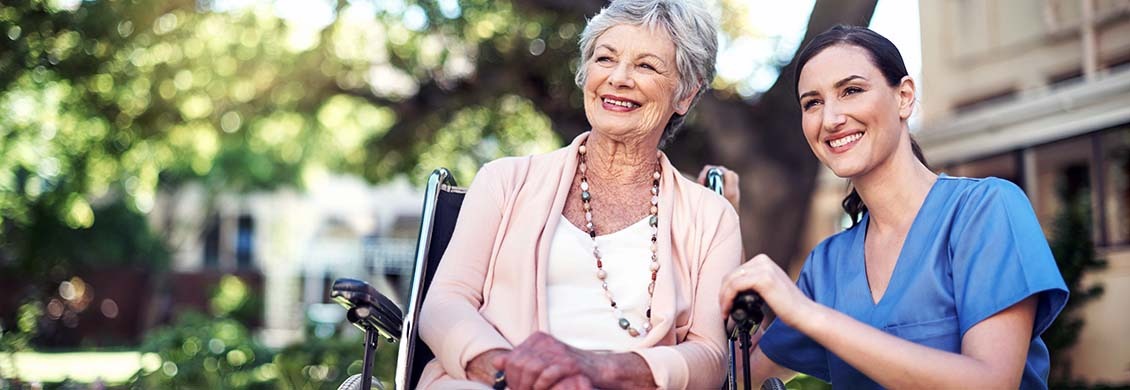 Professional caregiver with senior woman in wheelchair who returned home from hospital.