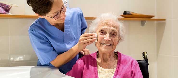 Caregiver providing hygiene services to an elderly woman.